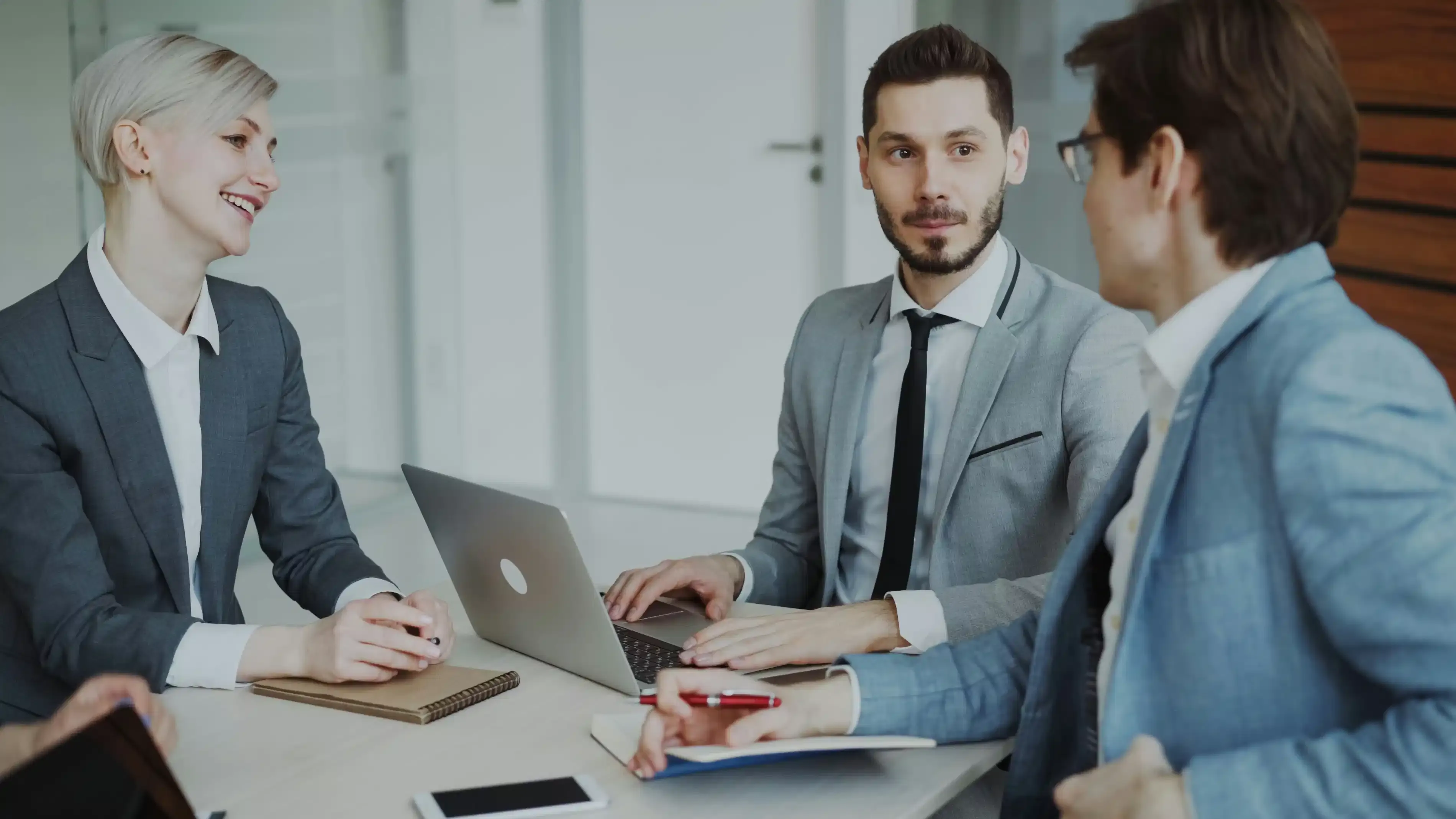 Partners collaborating around a laptop in a bright meeting room